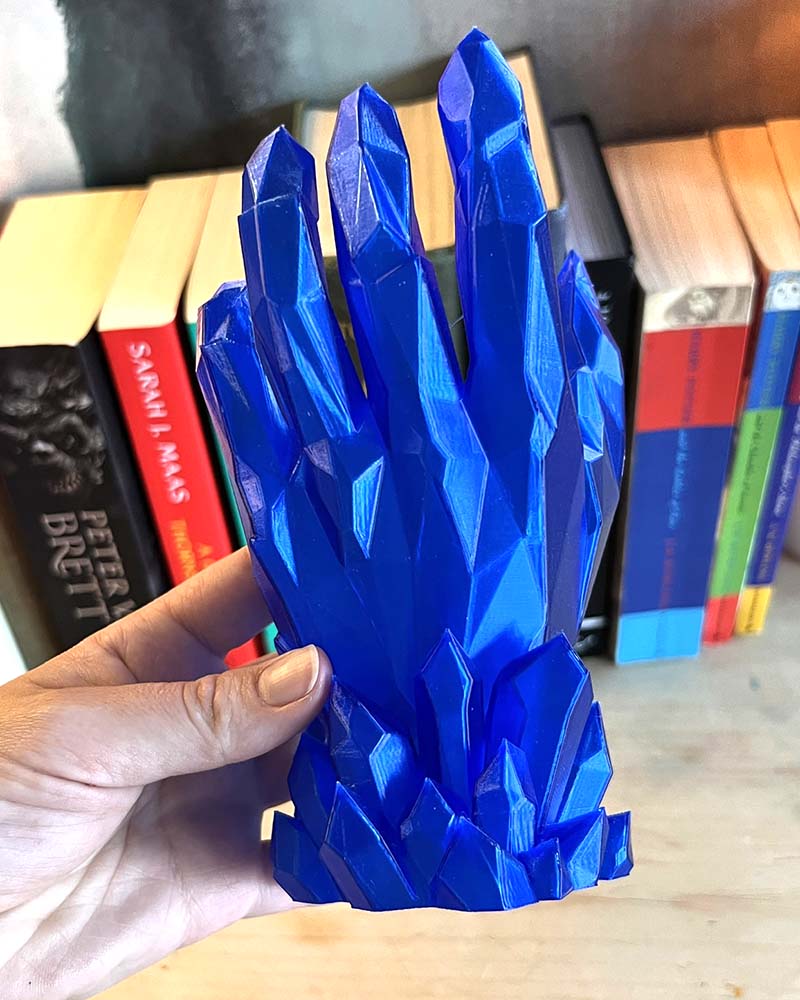 Blue crystal-like object held in front of books
