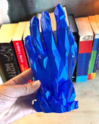 Blue crystal-like object held in front of books