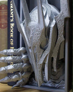 Side profile of Sauron’s helmet and gauntlet breaking through bookshelf