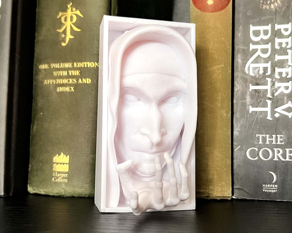 3D printed Valak The Nun from the Conjuring face between books – spooky Halloween decor from Ryan Does 3D