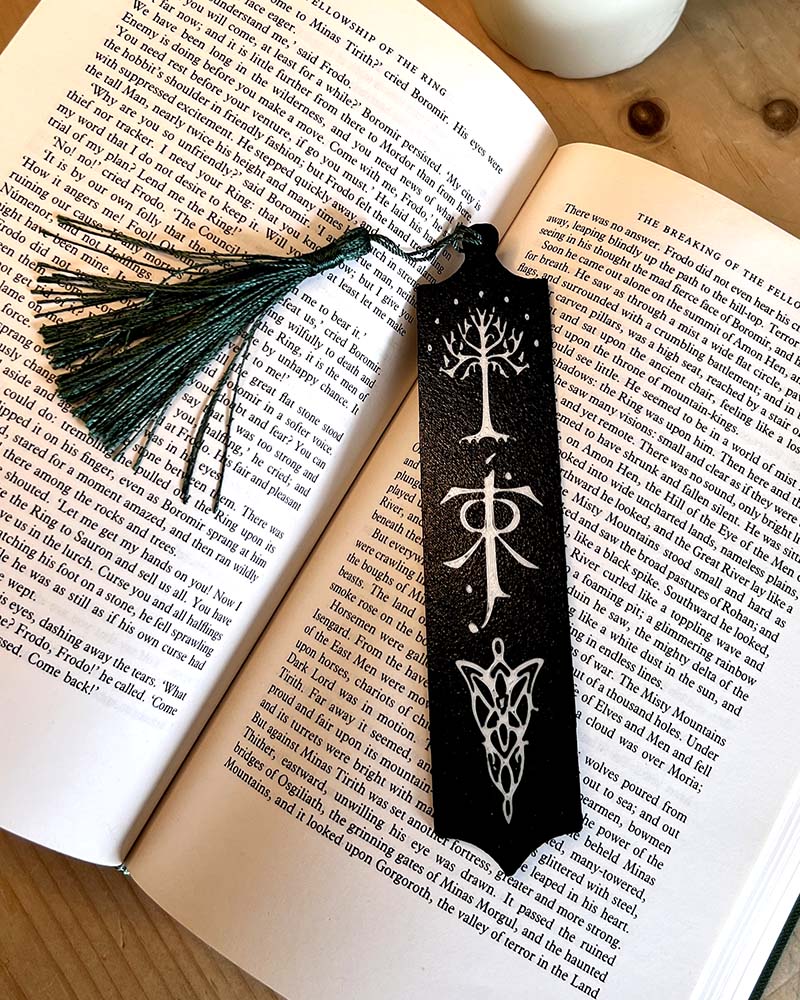 Fantasy bookmark with green tassel laid on open Lord of the Rings book in black and white coloured filament 3d printed