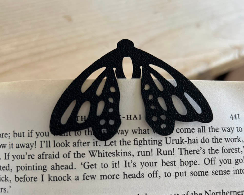 Black butterfly-shaped bookmark on a book page
